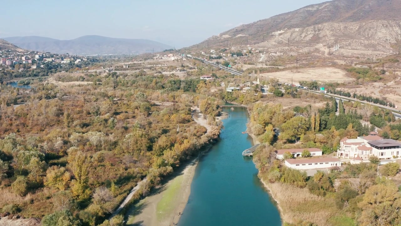 Vista aerea di un fiume che scorre attraverso un paesaggio autunnale con montagne e autostrada