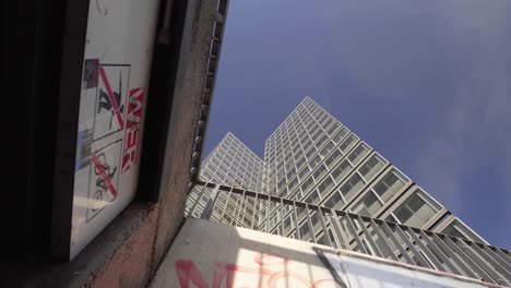 tilt up reveal shot of a tall modern skyscraper office building with graffiti and vandalism in the foreground, a bright clear blue sky in the background