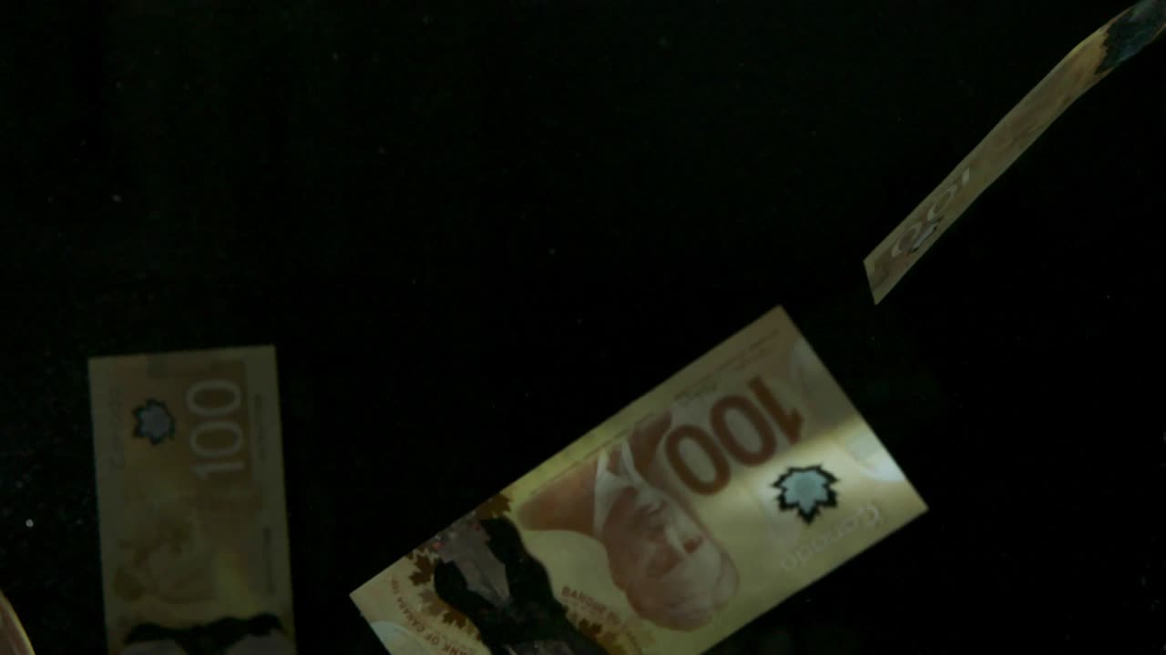 падающие летящие банкноты американского канадского доллара на черном фоне в 4k loopable. высококачественные падающие банкноты доллара в 4k. видео loopable