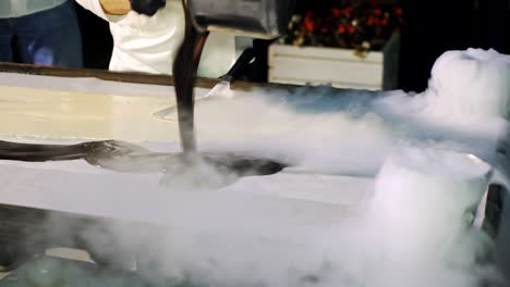 chief cook makes delicious black and white ice-cream on a big table.