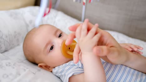 cute little baby holding mom hand lying in baby crib 4k