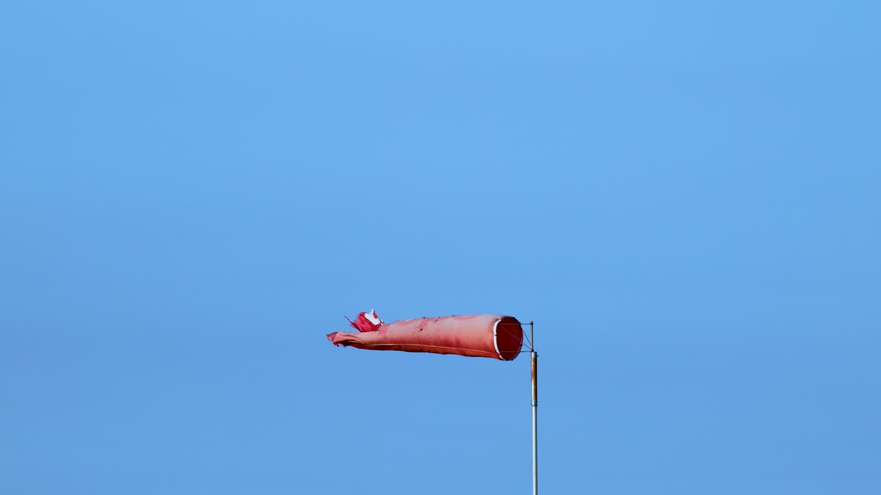 A red wind sock flutters against a clear blue sky, indicating wind direction and speed in Bellarine, Victoria