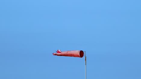 a red wind sock flutters against a clear blue sky, indicating wind direction and speed in bellarine, victoria