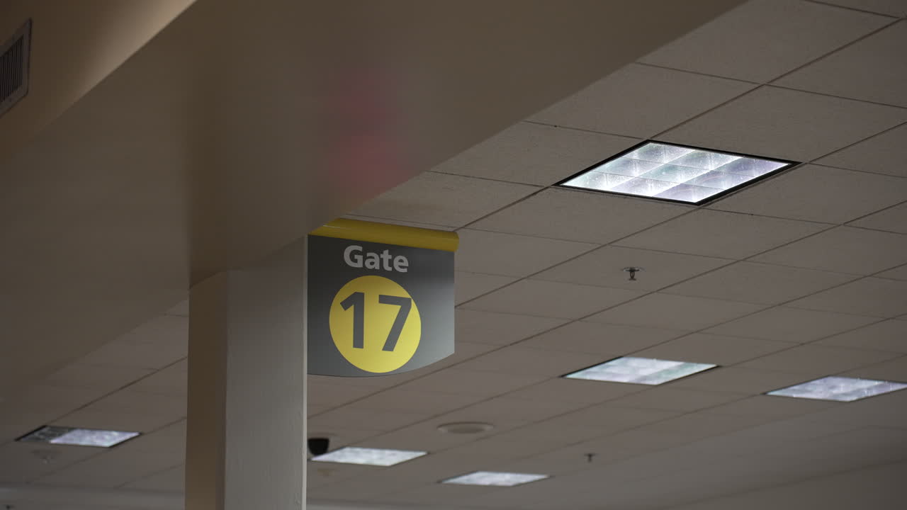 Gate 17 sign at an international airport for travelers next to a fire sprinkler or pendant
