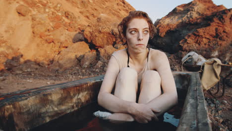 shivering woman sitting in dirty bathtub in post apocalyptic world