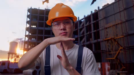hombre asiático trabajador mostrando tiempo de descanso manos gesto en el sitio de construcción