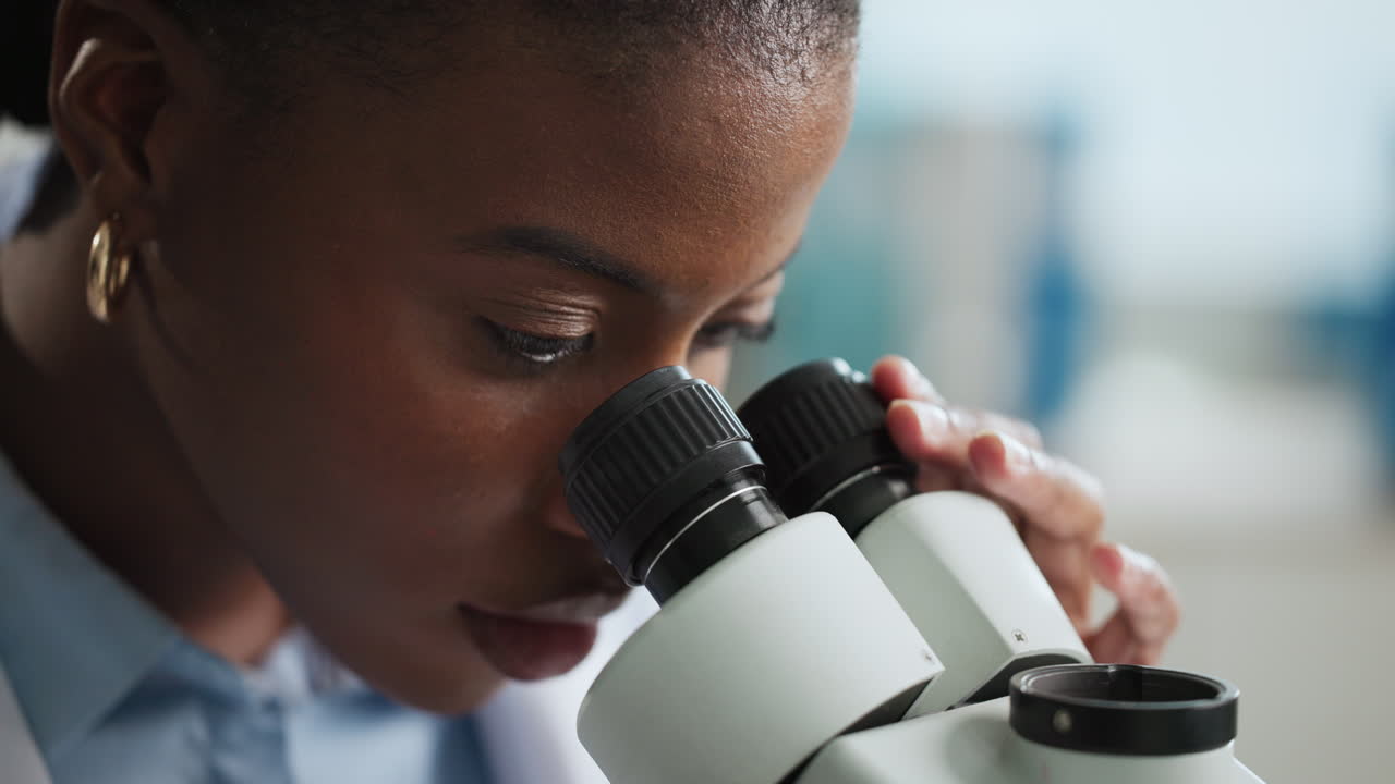 African American scientist using microscope in laboratory