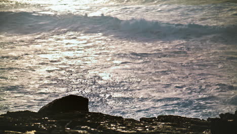 Olas-Poco-Profundas-Salpicando-Rocas-En-El-Primer-Plano-De-La-Mañana.-Agua-Brillante-Reflejando