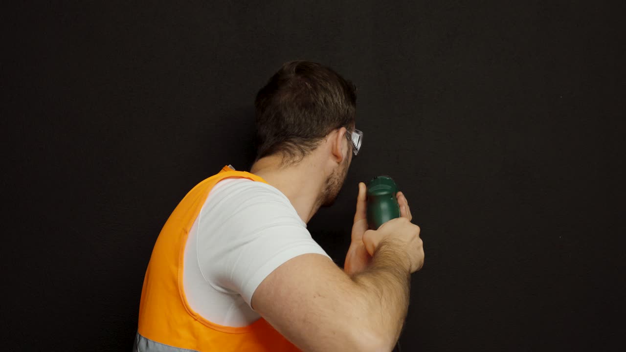 A worker puts on safety glasses before using a drill, demonstrating proper workplace safety and eye protection procedures