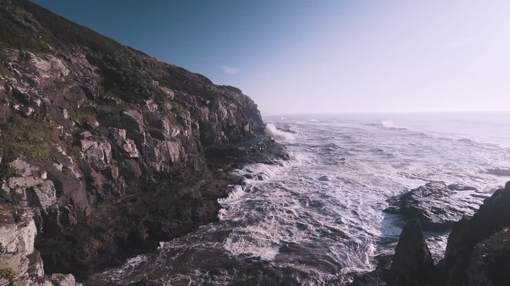 Onde che si infrangono sulla costa rocciosa al rallentatore all'alba