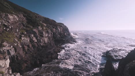 Waves-crashing-on-rocky-coast-on-slow-motion-at-sunrise