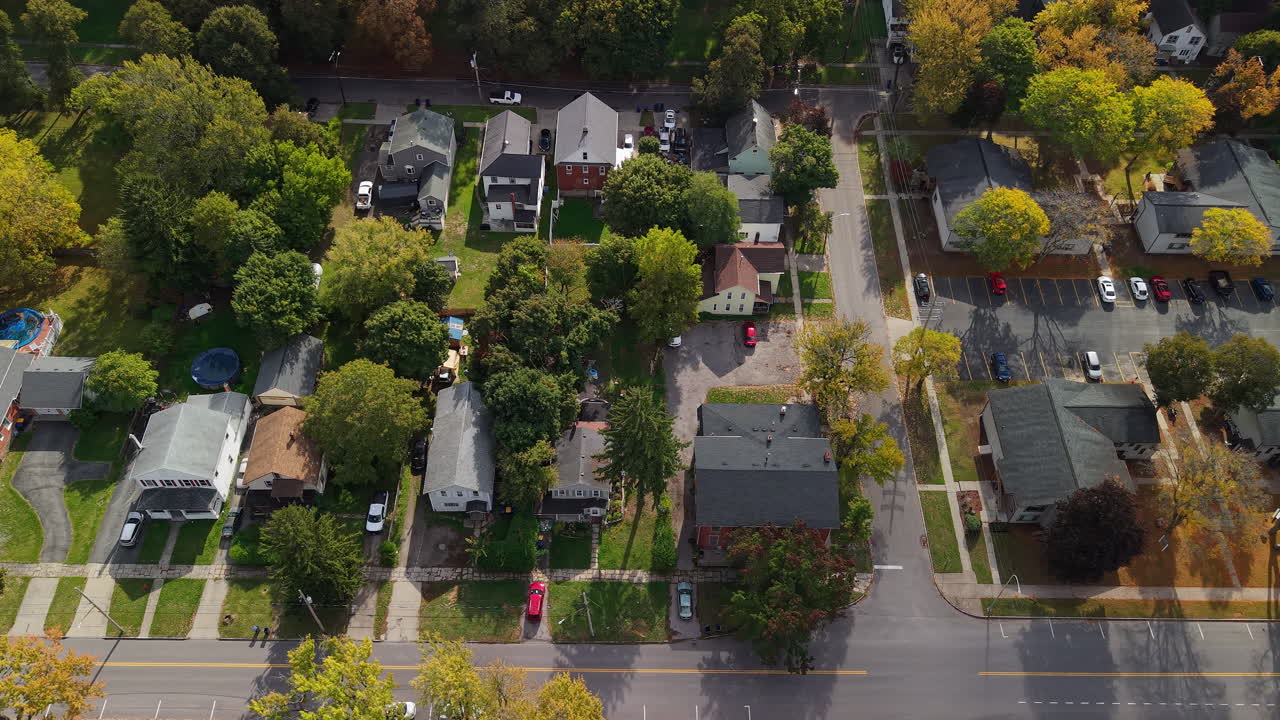 Aerial view of suburban residential neighborhood in USA with houses, tree lined streets, parked cars and colorful autumn foliage