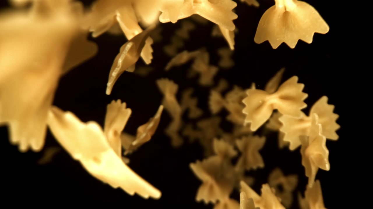 Pasta farfalle che cade al rallentatore su sfondo nero