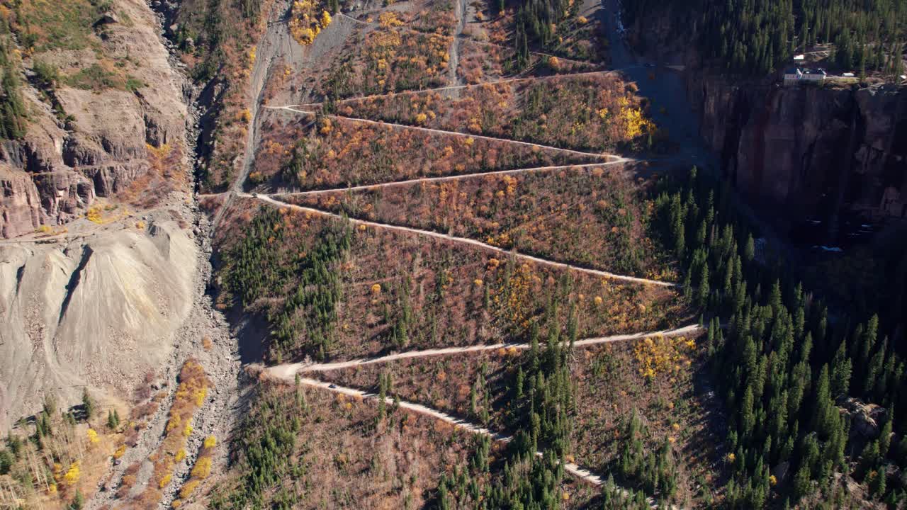 una toma de un dron revelando un oso negro pasando por un sendero en telluride, co.
