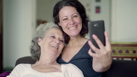 Mother-lying-on-daughters-shoulder,-having-video-chat-on-phone