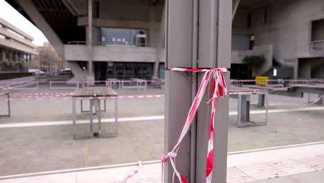 Closed-and-empty-bar-and-restaurant-terrace-in-London,-during-Covid-19-Coronavirus-pandemic,-barrier-tape-blown-by-the-wind,-in-slow-motion