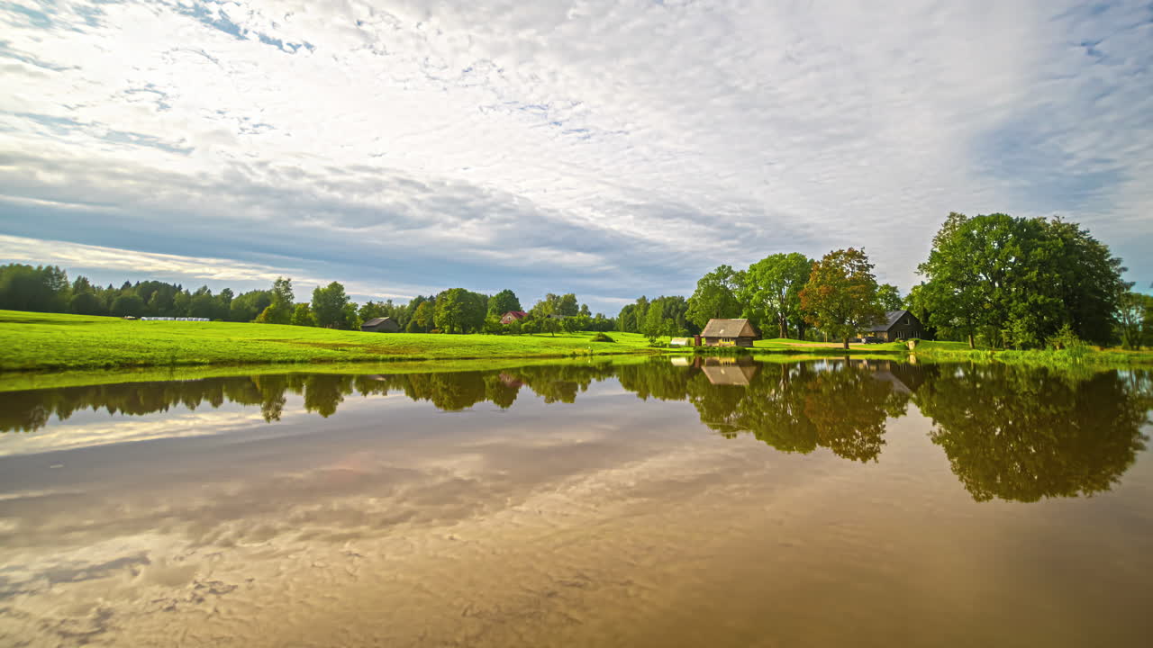 해가 지는 배경으로 호수 오두막 풍경 위의 구름의 놀라운 시간 경과