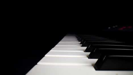 low profile wide angle macro of electronic keyboard - moving backwards aligned in the middle of the white keys, as the song assist lights the keys a red glow near far end of keyboard