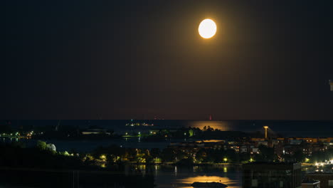 el lapso de tiempo de una luna llena brillante, sobre el golfo de finlandia, la noche en helsinki