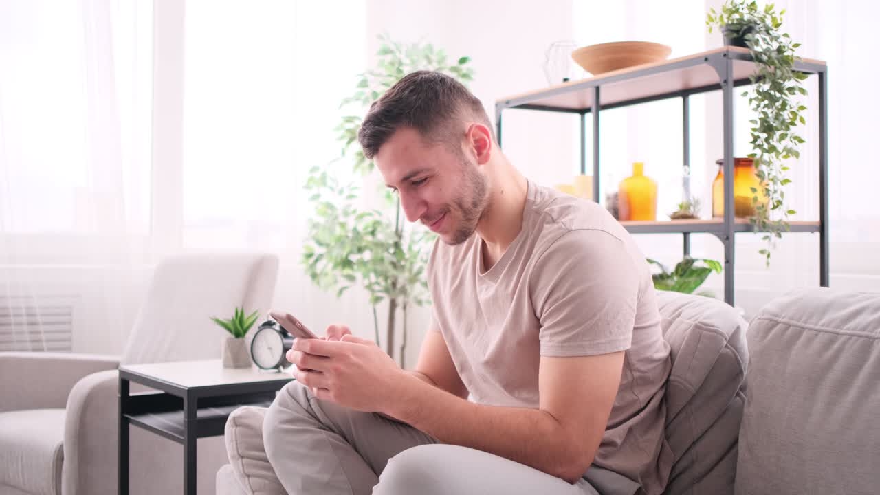 소파에 앉아 스마트폰으로 채팅하는 남자