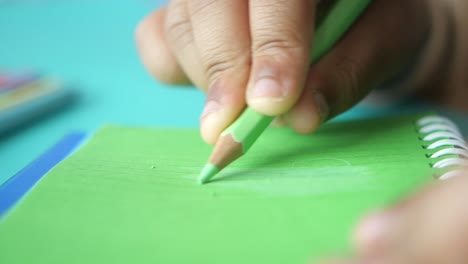 child drawing with a green colored pencil