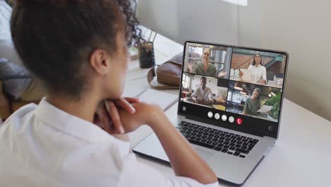 African-american-woman-using-laptop-for-video-call,-with-diverse-business-colleagues-on-screen