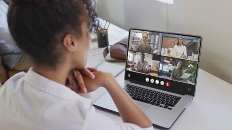 african american woman using laptop for video call, with diverse business colleagues on screen