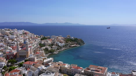 aerial: slow panning shot of asteria beach in ermoupoli of syros island, greece on a sunny day