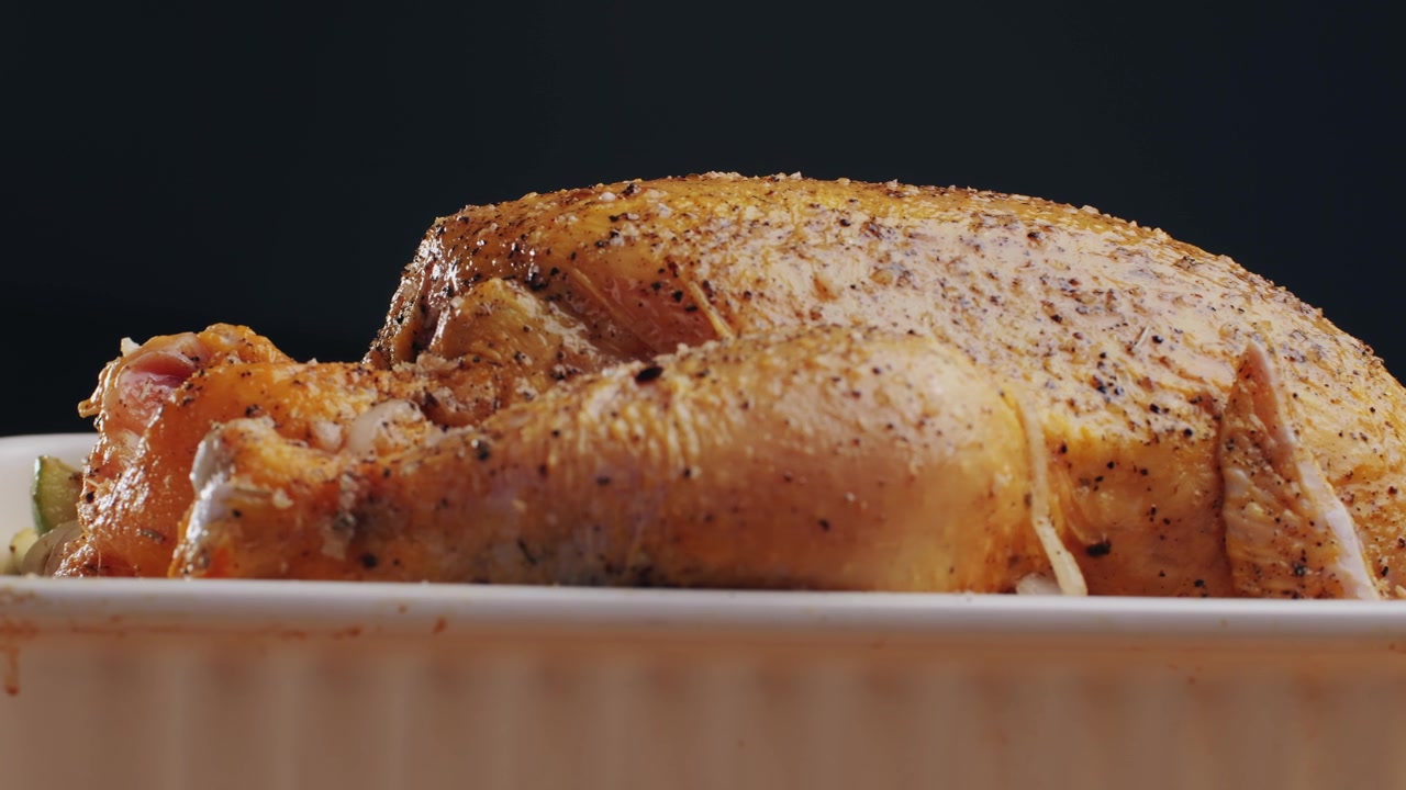 Gekruide rauwe hele kip in een witte ovenschaal