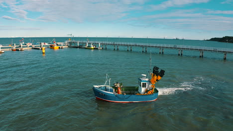 vista aérea de un barco de pesca en el mar con el muelle en el fondo