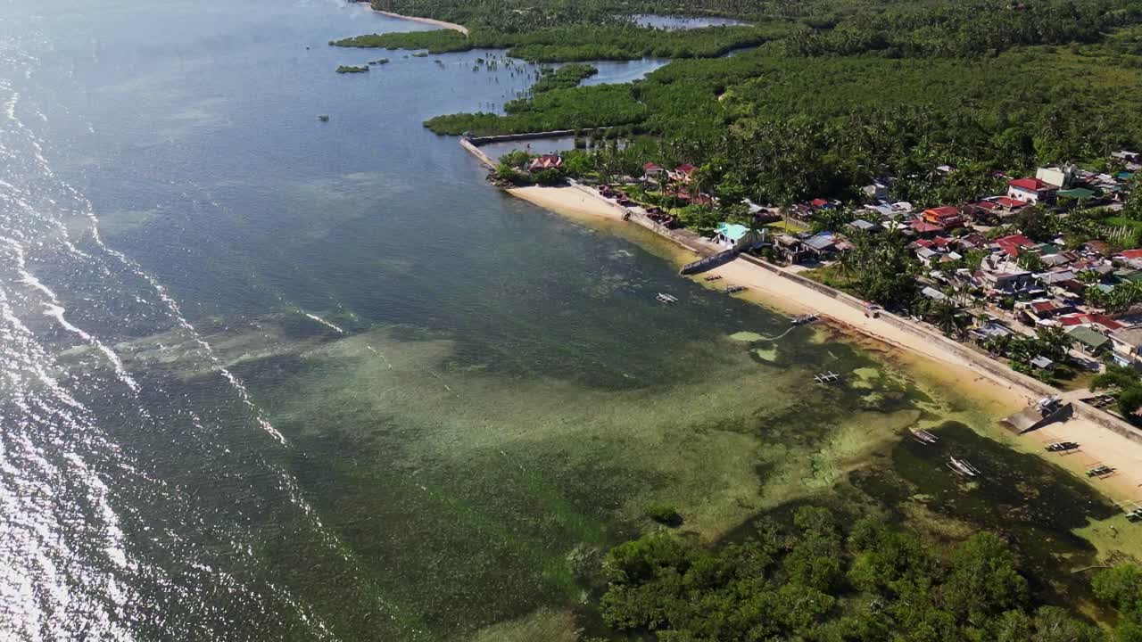 Overhead drone shot of local fisherman village facing vibrant coastline waters at tropical island Catanduanes, Philippines.