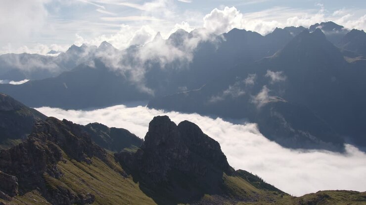 Wolken liegen in einem von Bergen umgebenen Tal