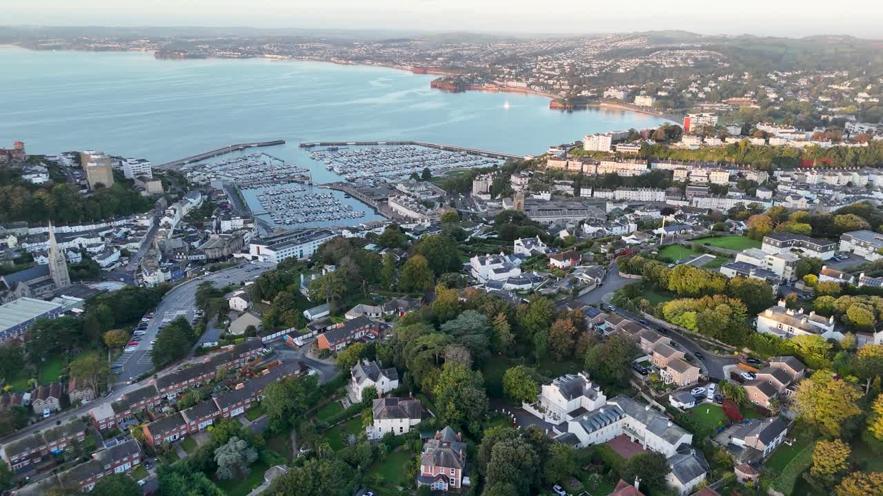 Cinematic aerial drone pedestal up movement over Torquay Marina and gulf showcasing boats harbor waterfront bay and coastal town in Devon England