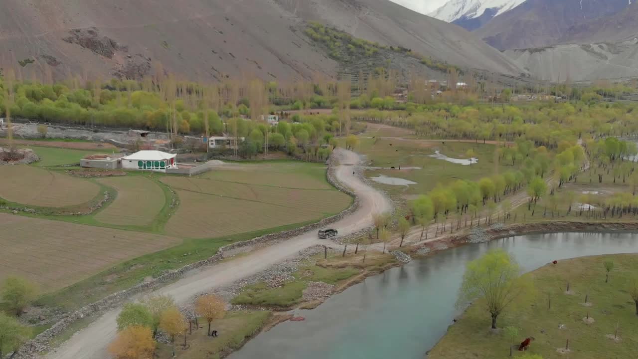 аэрофотосъемка внедорожника на сельской дороге у реки в районе долины гизер в пакистане