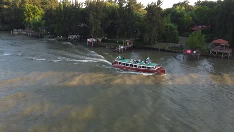 collective bus boat sailing along shores of parana river delta at sunset, argentina