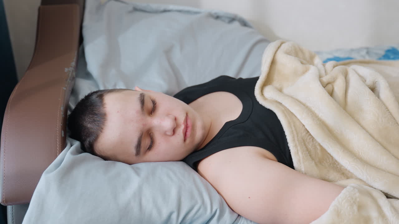 Close up of mother gently touching nose of sleeping boy resting under blanket as he slowly wakes up with warm smile showing tenderness family bond affection and comfort in bright cozy bedroom