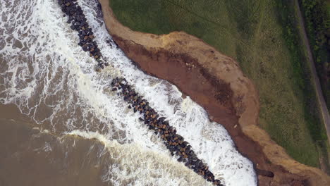 imágenes aéreas de drones de arriba hacia abajo en la marea alta cuando el mar choca contra las defensas marinas