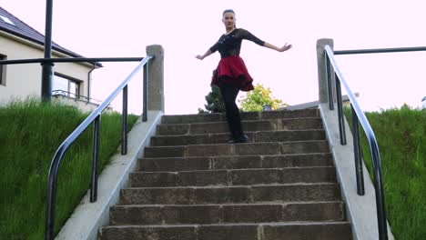 beautiful dancer gracefully climbs down the stairs in the park