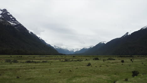 Racing-over-the-flatlands-of-Eglinton-Valley-towards-snow-covered-mountains,-New-Zealand