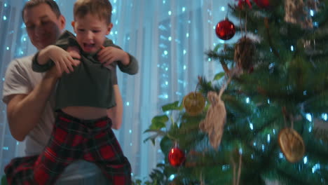 Vater-Hebt-Jungen-Hoch,-Um-Stern-Auf-Den-Weihnachtsbaum-Zu-Kleiden.-Hochwertiges-4K-Filmmaterial