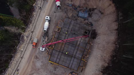 vista de pájaro de un sitio de construcción con trabajadores y camiones pasando