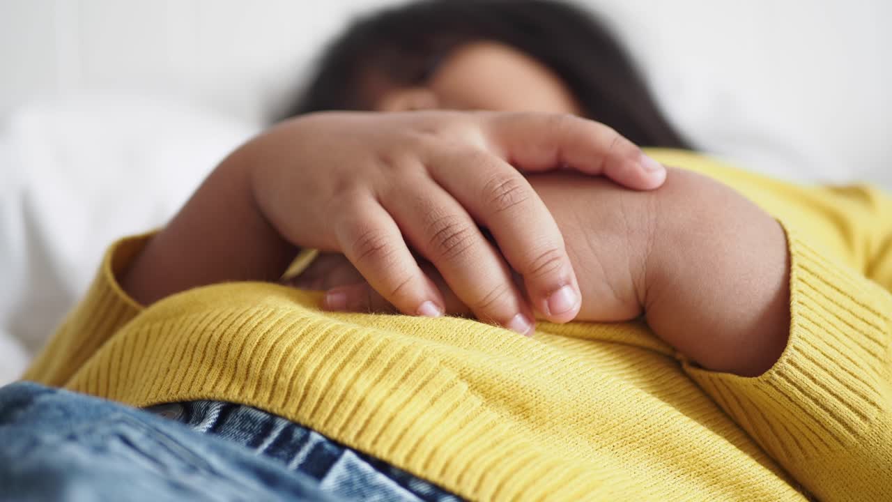 Young girl laying in bed with her hand on her stomach