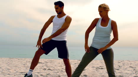 man and woman doing pilates on beach together