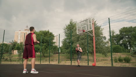 dos jugadores de baloncesto masculino entrenando juntos en una cancha de baloncesto al aire libre 2