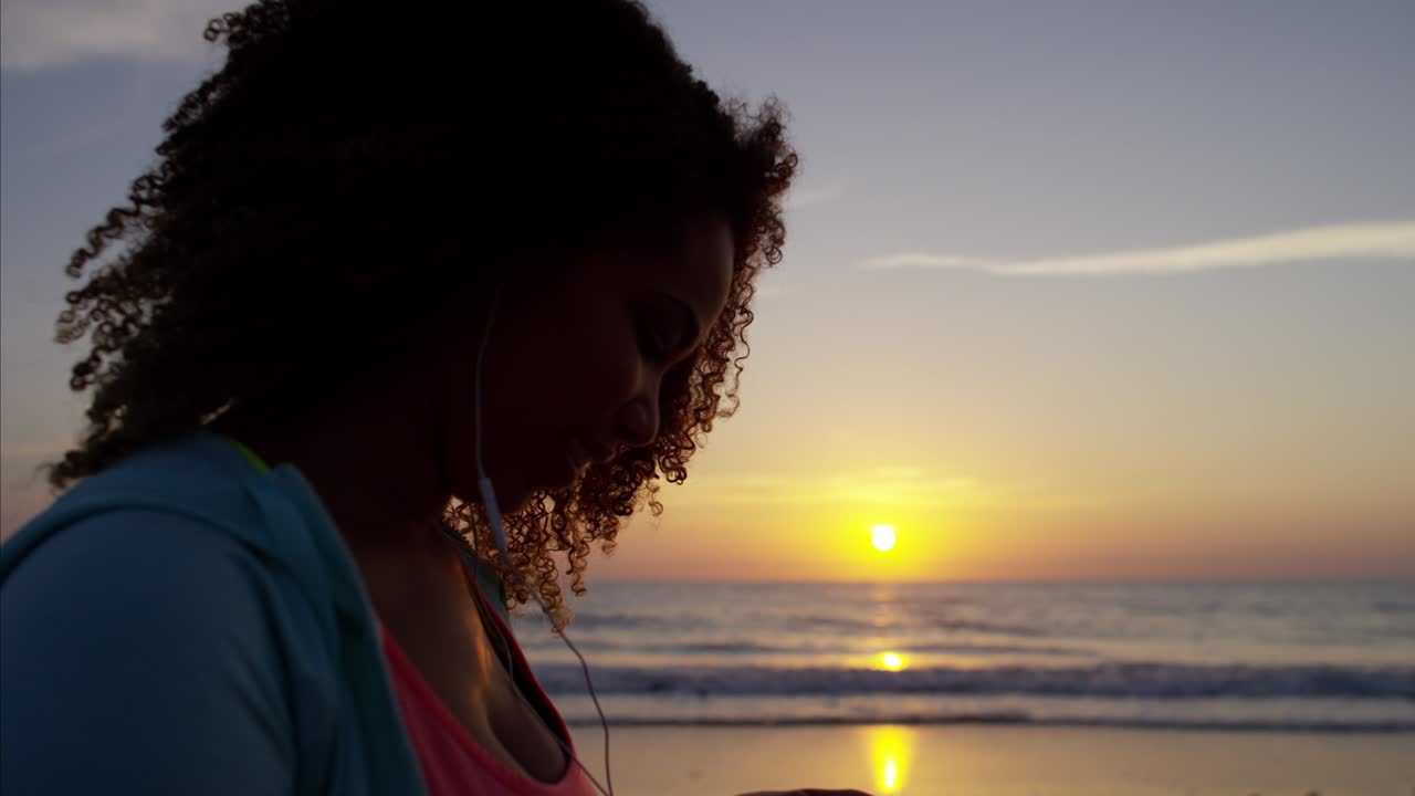 African American female with headphones dancing at sunrise