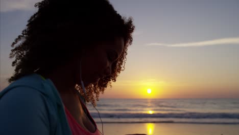 mujer afroamericana con auriculares bailando al amanecer