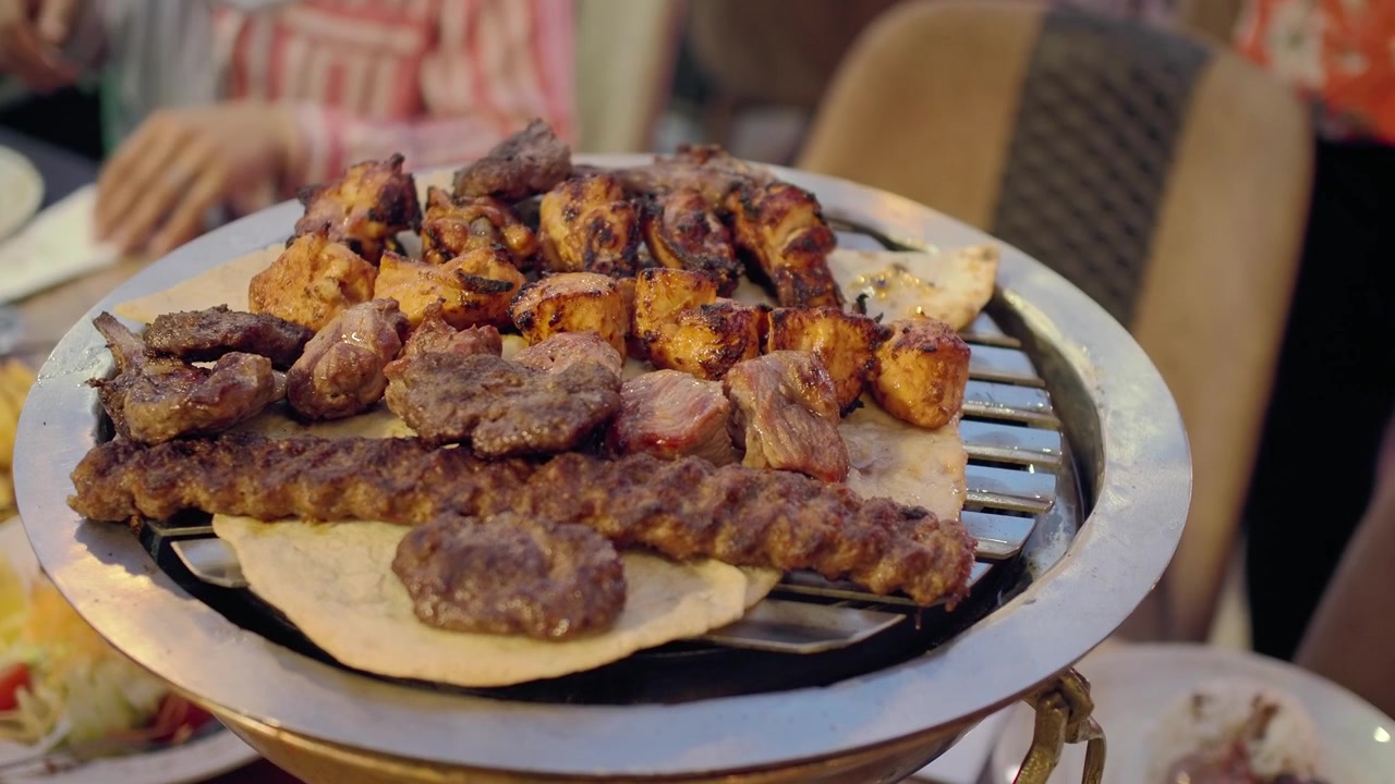 Persona che usa le pinze per servire carne alla griglia da un barbecue da tavolo