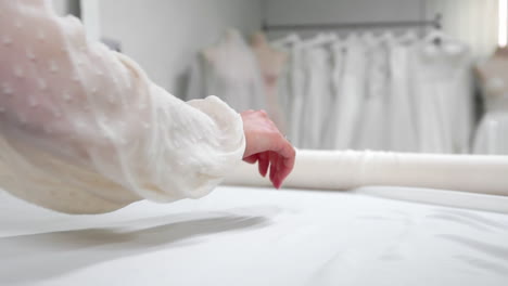 clothing designer is working with measurements on a studio table. shot on in 4k uhd . closeup deploy a skein of white fabric in white and light-colored sewing in slow motion.