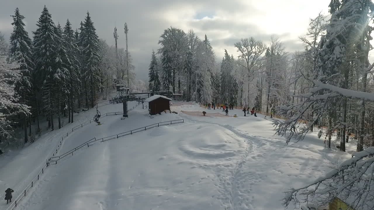 Winter alpine ski resort. Snow forest and skiers on a ski lift pov. Aerial view