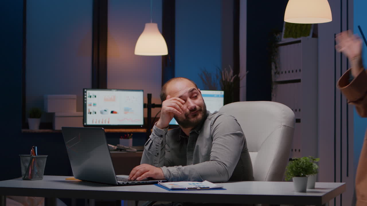 Exhausted businessman checking marketing statistics on laptop computer